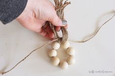 a person stringing up some wood beads on a white surface with twine around them