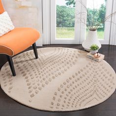 a white rug with an orange chair in front of a window and a plant on the floor