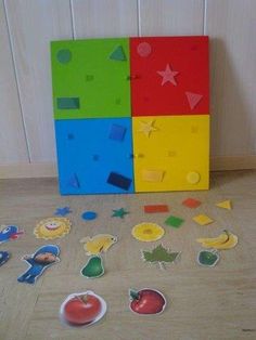 several pieces of cut out paper sit on the floor next to each other in front of a colorful box