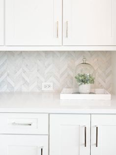 a kitchen with white cabinets and marble backsplash