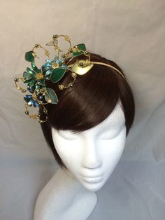 Delicate glass resin floral fascinator perfect for the guest who wants something unique and stunning. This design is a beautiful selection of glass effect leaves and flowers teamed with crystal swirls and set onto a fine comfort base tiara band. As with all our designs, this piece can be made exact to the image or in any colour combination to match in with your outfit. If a specific colour is required customers can message over an image of their outfit and accessories, or if time allows customer Elegant Headpiece With Teardrop Crown For Gift, Elegant Teardrop Crown Headpiece For Gifts, Elegant Headpieces With Teardrop Crown For Gift, Whimsical Crown-shaped Headband For Gifts, Whimsical Crown Headband As Gift, Elegant Headpiece With Pinched Crown For Gift, Elegant Handmade Teardrop Crown Headpiece, Elegant Round Crown Headpiece For Gifts, Elegant Round Crown Headpiece As Gift