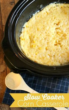 slow cooker corn casserole in a crock pot with wooden spoons