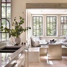 a kitchen filled with lots of counter top space next to a window covered in plants