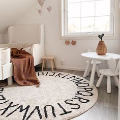 a white bedroom with a round rug on the floor and two small tables next to it