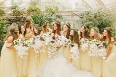 a group of women standing next to each other in front of a glass house holding bouquets