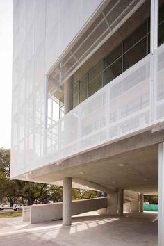 an empty parking lot in front of a building with white walls and balconies