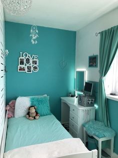 a bedroom decorated in blue and white with a teddy bear sitting on top of the bed