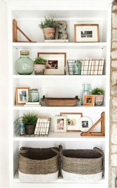 a white book shelf filled with baskets and pictures