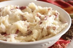 a white bowl filled with mashed potatoes sitting on top of a red table cloth