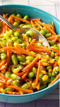 a blue bowl filled with carrots and peas