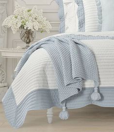 a bed with blue and white bedspreads, pillows and blankets on top of it