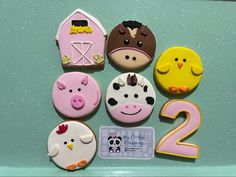 decorated cookies with farm animals and numbers are displayed on a green surface, including one for the number two