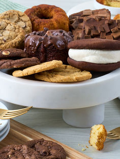 an assortment of cookies, ice cream and chocolate donuts on a platter with gold utensils