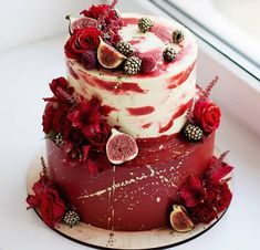 a three tiered cake decorated with flowers and figs