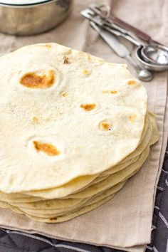 a stack of flour tortillas sitting on top of a napkin next to a bowl