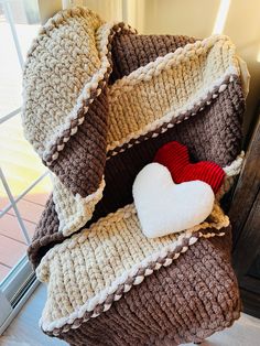 a pile of knitted pillows with a heart on top