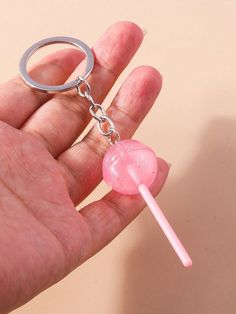 a hand holding a pink lollipop shaped keychain