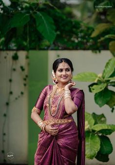 a woman in a purple sari posing for the camera with her hand on her hip