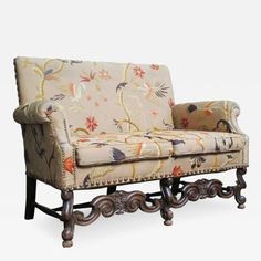 an ornately upholstered couch with floral fabric and wood trimmings on the arms