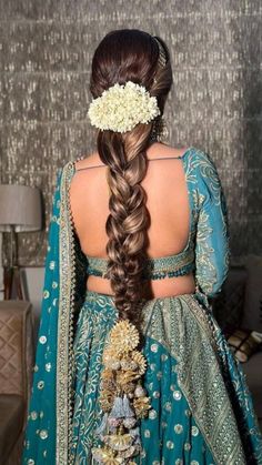 a woman with long hair wearing a blue dress and flowers in her hair is shown from the back