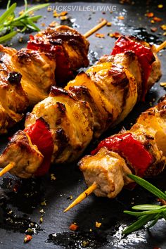 chicken skewers with ketchup and herbs on a black surface