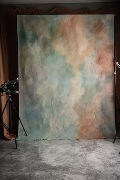 an empty photo studio with a backdrop and two lights on the floor, in front of a curtain