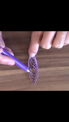 a person holding a purple plastic object in their left hand on a wooden surface with the other hand reaching for it