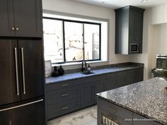 a kitchen with granite counter tops and stainless steel appliances, along with dark wood cabinets