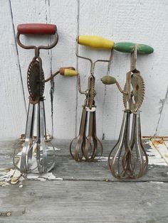 three metal utensils sitting next to each other on top of a wooden table