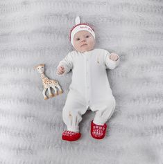 a baby is laying down with a giraffe toy in his hand and wearing red boots