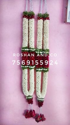 two white and red flowers hanging from the side of a wall with bells on it