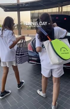 two girls in white shirts and shorts are getting into a car with their back to the camera