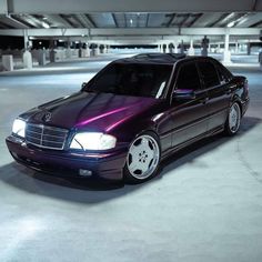 a purple car is parked in an empty parking garage with white rims and chrome wheels