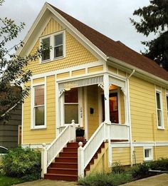 a yellow house with stairs leading to the front door