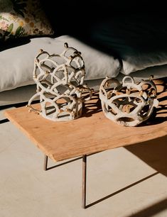 two decorative objects sitting on top of a wooden table in front of a couch with pillows