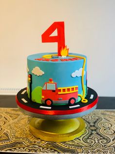 a birthday cake with the number one on it and a fire truck in the background