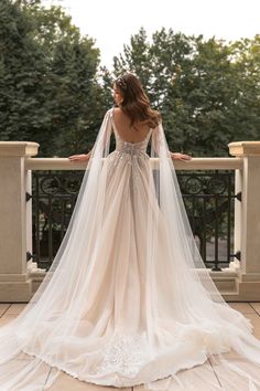 a woman in a wedding dress standing on a balcony with her back to the camera