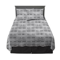 a bed with grey sheets and pillows on it