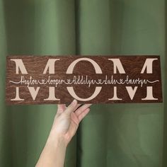 a person holding up a wooden sign that says mom