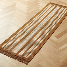 a brown and white rug sitting on top of a wooden floor next to a hard wood floor