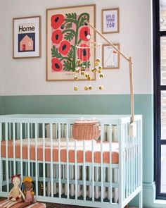 a baby crib in front of a window with pictures on the wall above it