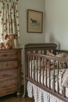 a teddy bear sitting on top of a crib next to a dresser and window