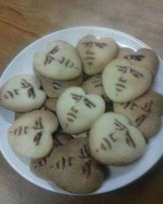 a bowl filled with cookies that have faces drawn on them and words written in cursive writing