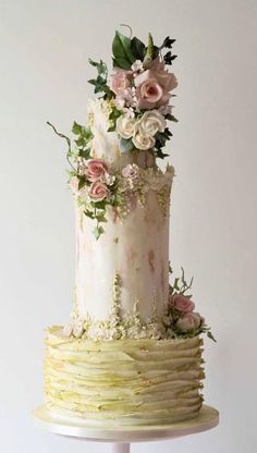 a three tiered cake with pink flowers on top and greenery around the edges