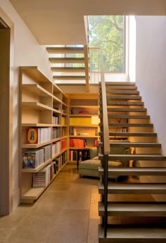 there is a stair case in the middle of this room with bookshelves on both sides