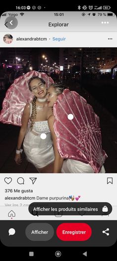 two girls are hugging under an umbrella in the street at night, one girl is wearing a white dress and the other has pink parasol