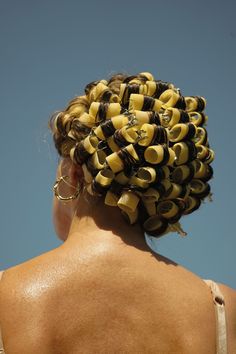 the back of a woman's head with hair clips in her hair, against a blue sky