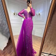 a woman taking a selfie in front of a mirror wearing a purple evening gown