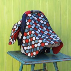 a polka dot bag sitting on top of a blue stool next to a green wall