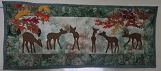 a wall hanging with several giraffes and leaves on it's side